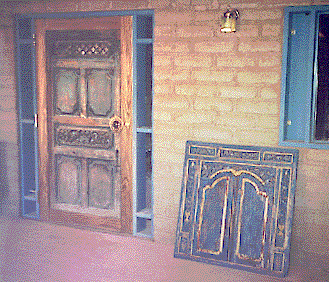 [Exterior view of door and window framing with the door installed and the shutters ready to be inset: 47k]